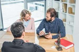 concentrated couple discussing contract together with lawyer in office